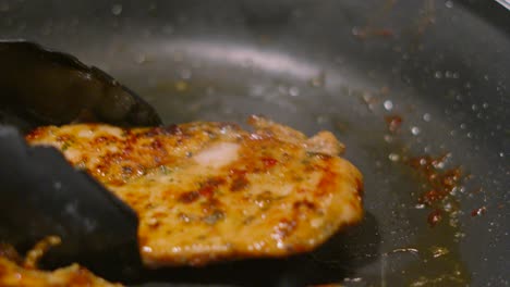 chinese chicken steaks being cooked in hot pan in restaurant kitchen using tongs to flip over fillets. food photography footage 4k.