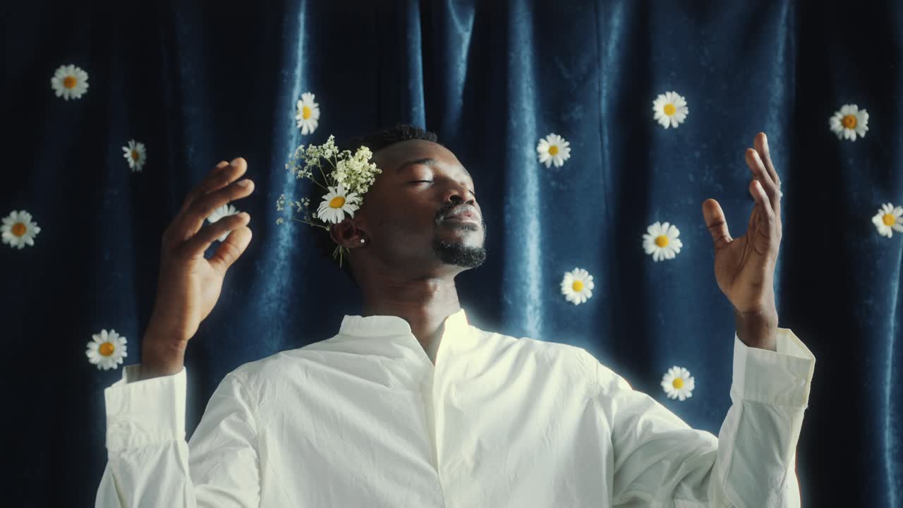 Tranquil Black Man Meditating against Blue Curtain with Daisies