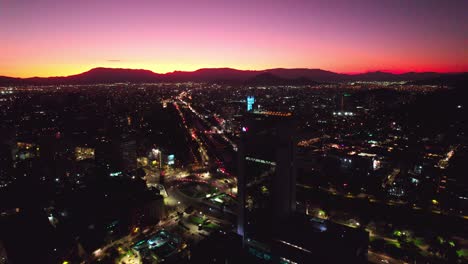aerial drone fly above sunset in barrio italia santiago chile providencia magenta and yellow skyline and illuminated neighborhood establishing shot