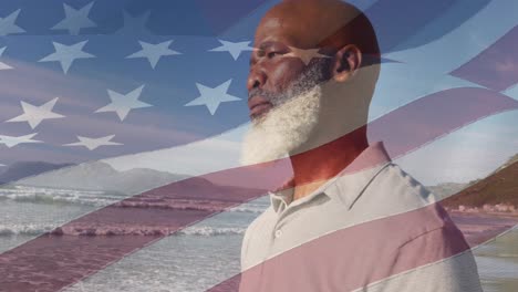 animation of flag of united states of america over senior african american man on beach