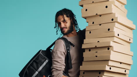 portrait of smiling pizza delivery man holding takeaway orders, blue background