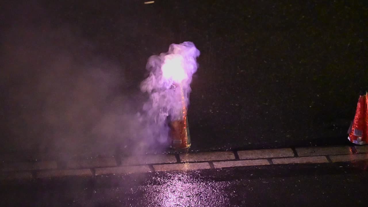 a firework has been lit and begins to produce smoke and warm colors during a Swiss party