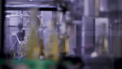 bottles filled with white wine, handled and carried by an automated conveyor machine at a winery