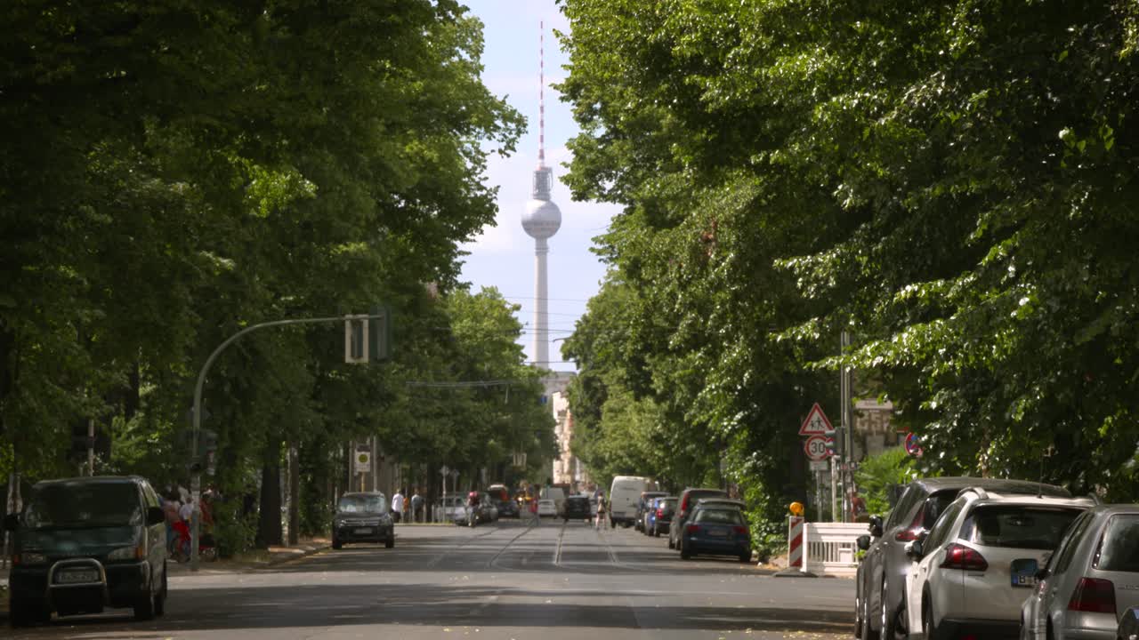 Berlins fjernsynstårn i sommerligt bylandskab mellem en grøn allé af træer, Tyskland