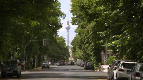 berliner fernsehturm in urbaner sommerlandschaft zwischen grünen baumalleen, deutschland