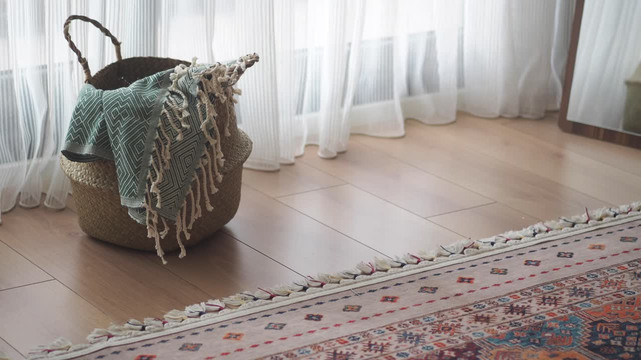 Cesto con coperta e tappeto su pavimento in legno