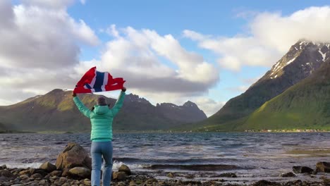 mujer con una bandera de noruega ondeando en el fondo de la naturaleza