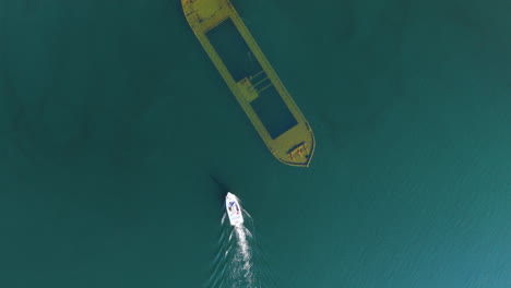top down drone shot of a boat arriving at a shipwreck at lake saimaa, finland