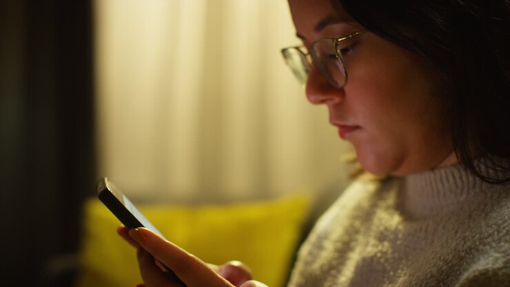 Close Up Of Young Woman Spending Evening At Home Sitting On Sofa With Mobile Phone Scrolling Through Internet Or Social Media 1