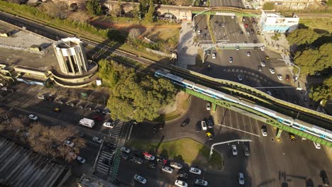 aerial top down shot of traffic on road and driving train over bridge during rush hour in buenos aires