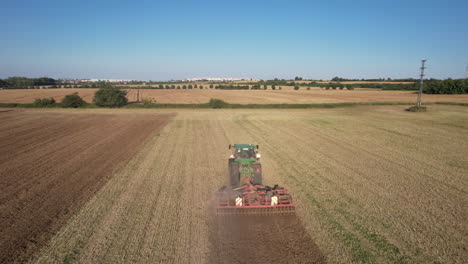 vista aérea, tractor arando en tierras agrícolas secas y polvorientas en un día soleado, disparo de drones