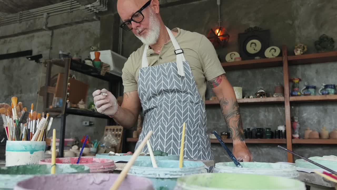 Artigiano esperto che dipinge a mano ceramiche in uno studio artistico