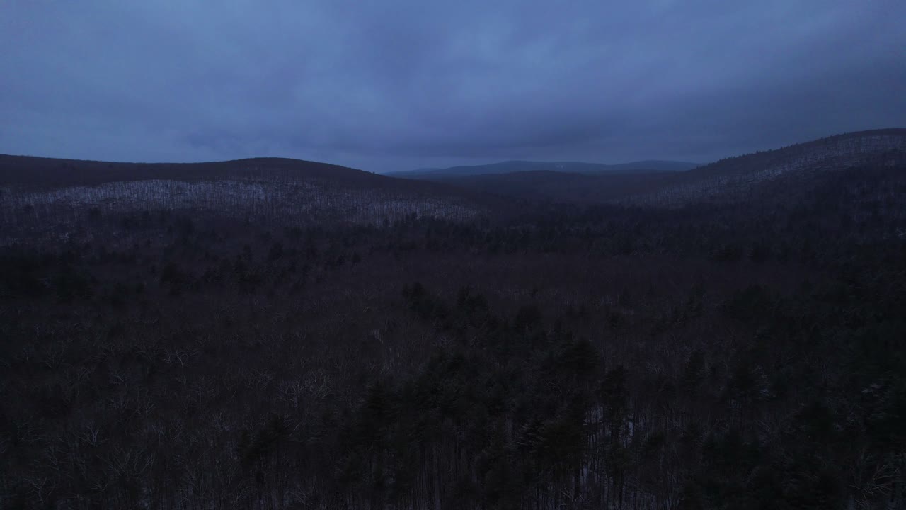 Aerial drone video footage of nightfall in the snowy Appalachian mountains during winter, in the Catskill Mountains sub-range