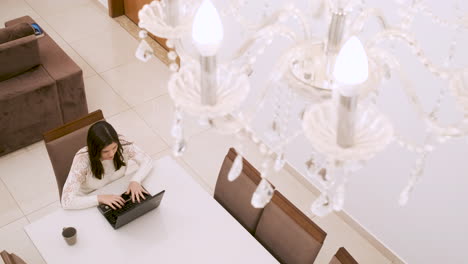 Captura-De-Pantalla-De-Una-Mujer-Caucásica-Trabajando-Desde-Casa-En-Una-Laptop,-Bajo-Una-Lámpara-De-Araña