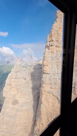 passenger points at rocky peaks as cable car climbs in terraza dolomiti route