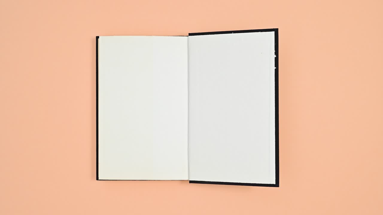 Black hardcover retro book rotating and opening on two sides on orange theme. Stop motion flat lay