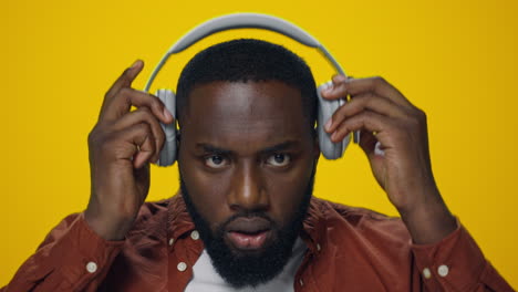 portrait of surprised african guy listening music on headphones in studio.