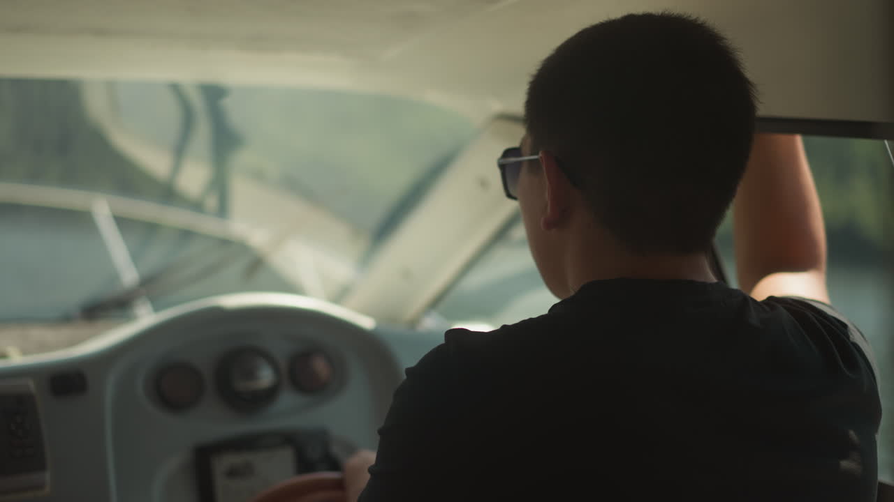 el capitán confiado con gafas de sol conduce el yate de pie en la cabina. el marinero controla el barco a motor en un crucero marítimo en un día soleado. el capitán del barco turístico