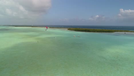 dos kitesurfistas que usan cometas blancas y rojas para volar en el archipiélago de salinas los roques