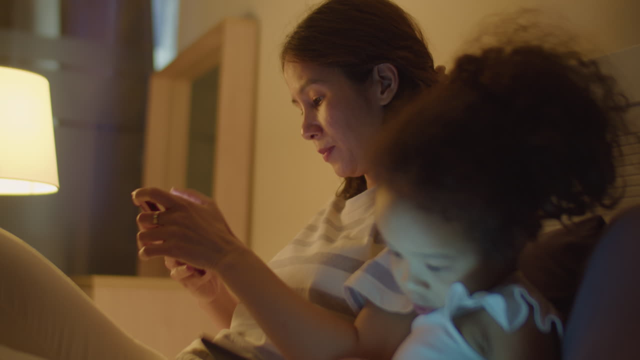Asian Mom and Little Daughter Using Gadgets in Evening