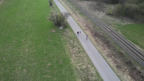 aerial tracking shot of a family rollerskating at the side of a railway track