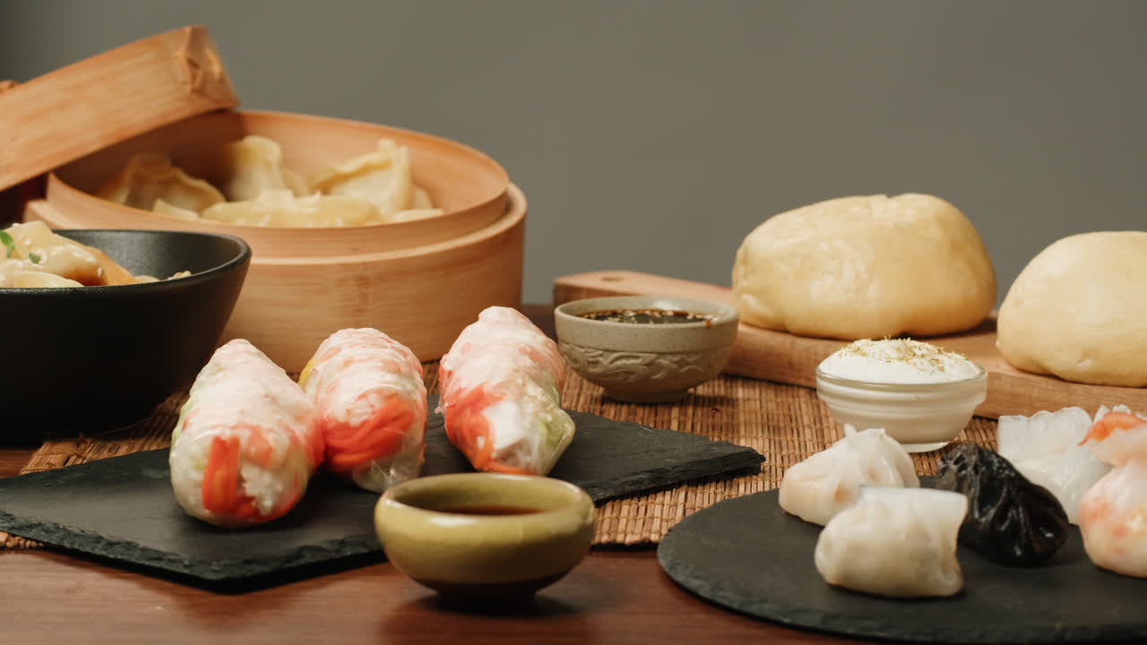 Variety of Asian Dumplings, Spring Rolls, and Buns on a Table