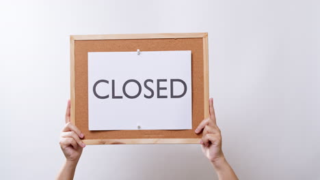 Woman's-hand-shows-the-paper-on-board-with-the-word-CLOSED-in-white-studio-background-with-copy-space