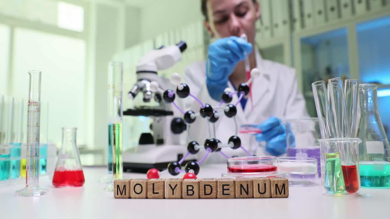 Kimyager, kırmızı sıvıyı petri kabına pipetle damlatıyor.