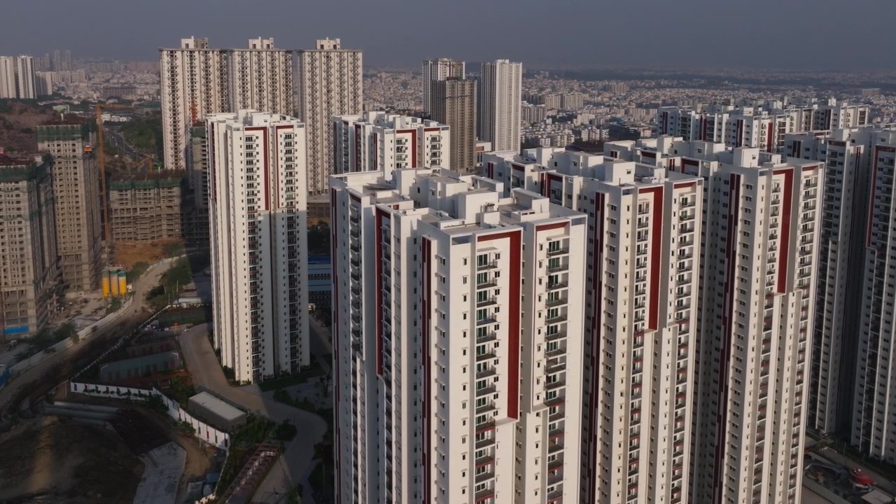 Edifícios Aparna Zenon Tower com construções em andamento e apartamentos Sukhii Ubuntu em Khajaguda, Hyderabad, Telangana, Índia. Durante o dia, tomada em arco, filmagem de drone, 4K.
