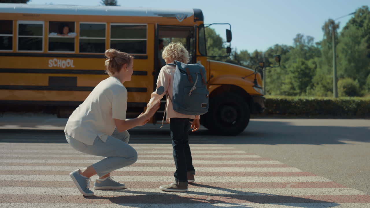 Moeder geeft high five aan zoon. Schooljongen die vaarwel zegt aan boord van de schoolbus alleen