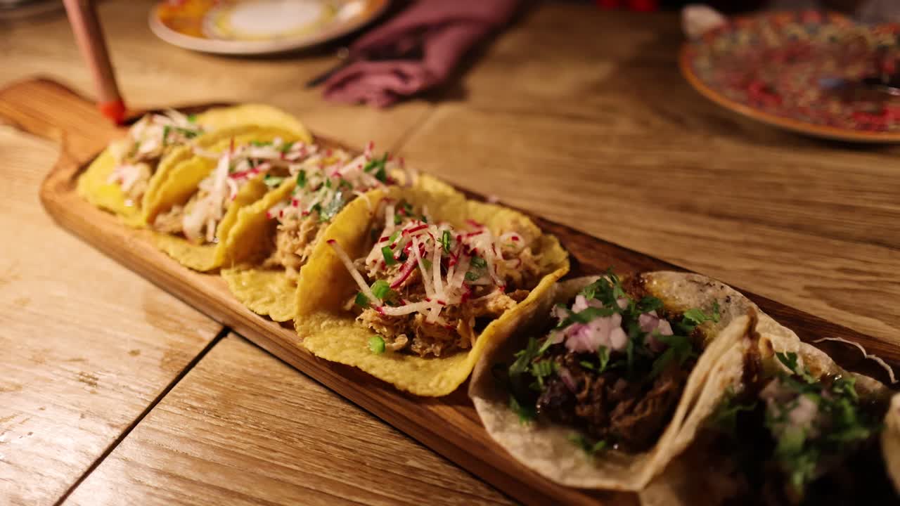 A wooden platter of assorted tacos on a rustic table under warm lighting in a Bangkok restaurant