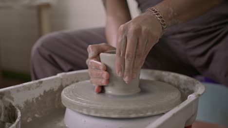 craftsperson shaping pottery on a wheel, hands detailed in clay