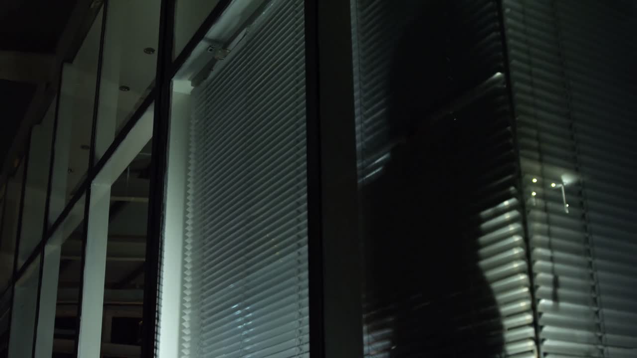Businessman looking through window blinds