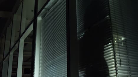 un hombre de negocios mirando a través de las persianas de la ventana.