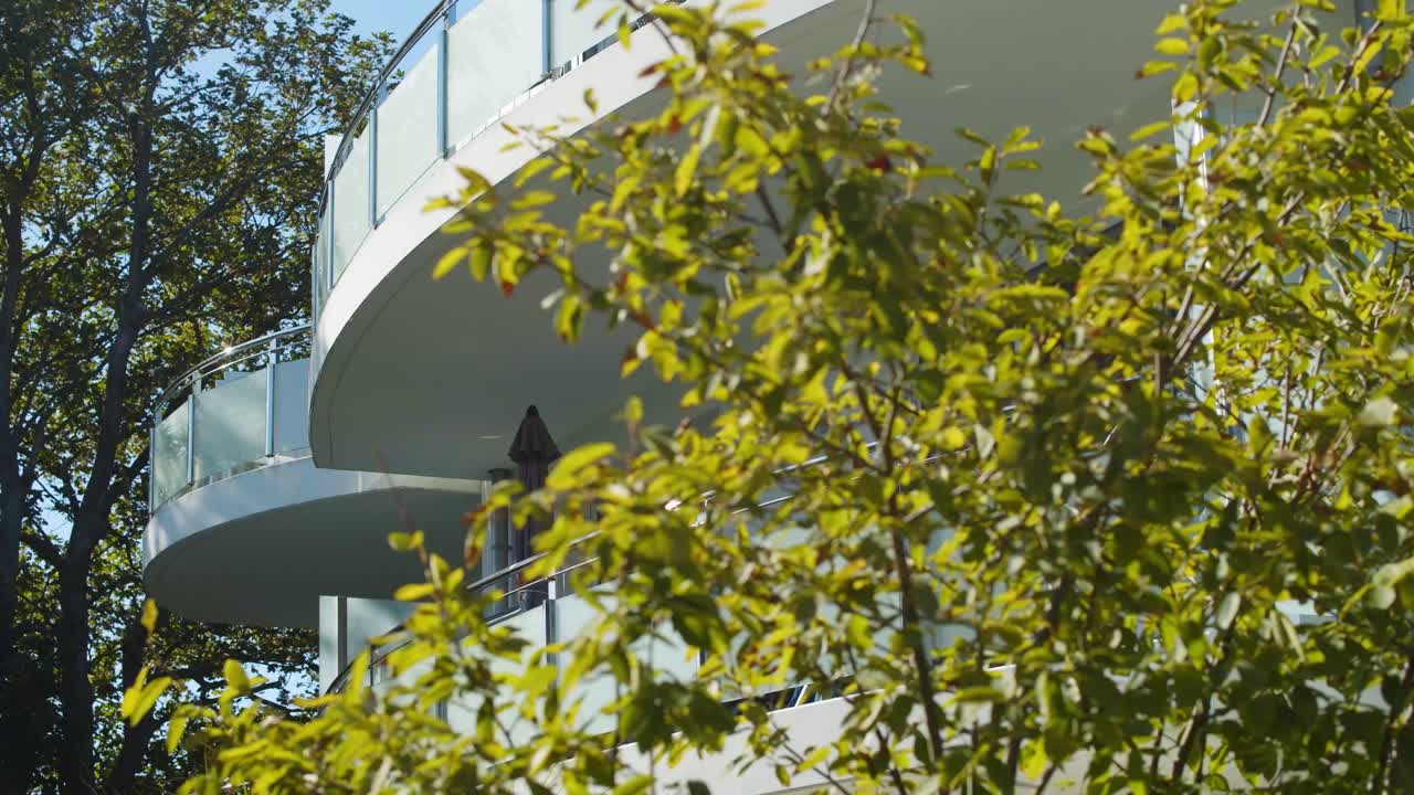tracking shot of big round modern balconies with plants in the foreground