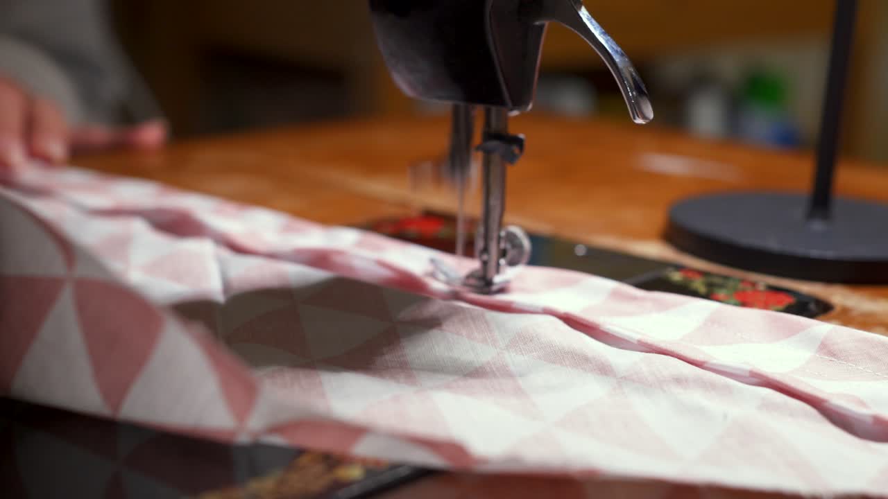 Close up shot of old vintage sewing machine stitching on fabric,hands of an elderly woman in the shot 4K