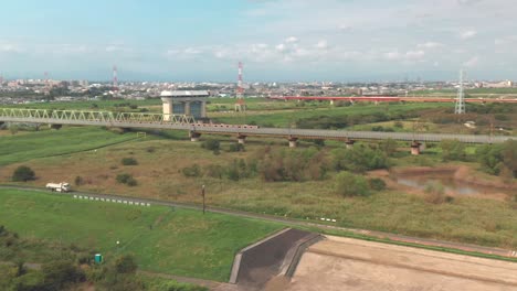 Lange-Zugüberfahrt-Durch-Die-Eisenbahnbrücke-über-Den-Arakawa-fluss-Mit-Blick-Auf-Die-Stadt-Fujimi-Unter-Dem-Strahlend-Blauen-Himmel-In-Saitama,-Japan