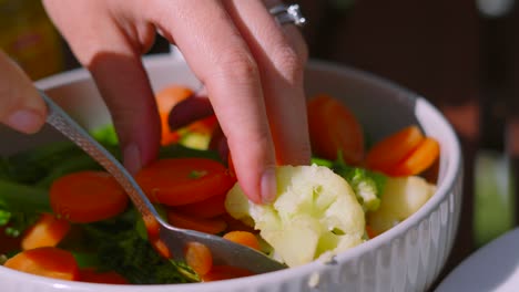 fresh vegetables being picked up by woman female hands with spoon including tenderstem broccoli, carrots, cauliflower. healthy food in natural light.