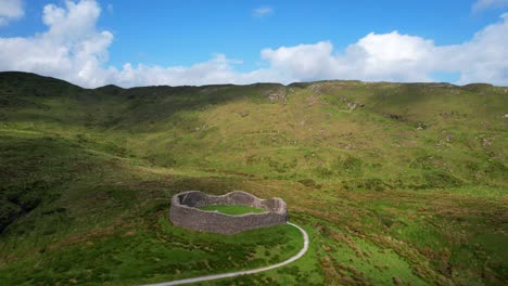 Aerial-shot-flying-back-over-Staigue-Stone-Fort-amidst-lush-greenery,-Ireland