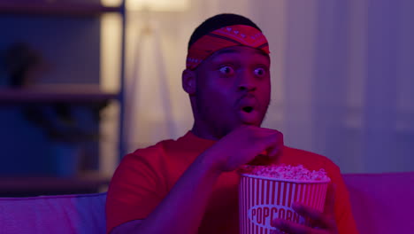 man watching a movie with popcorn, surprised