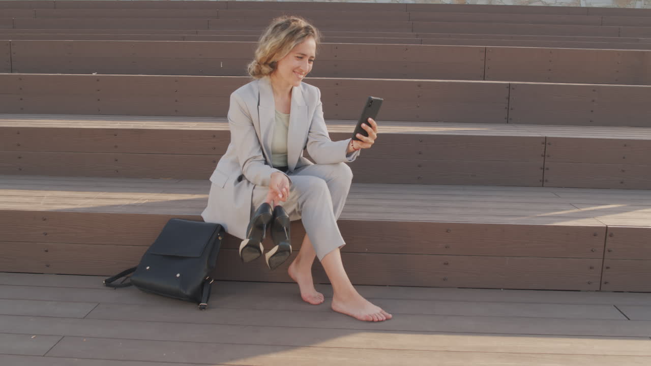 Businesswoman Resting Outdoors with Shoes in Hands