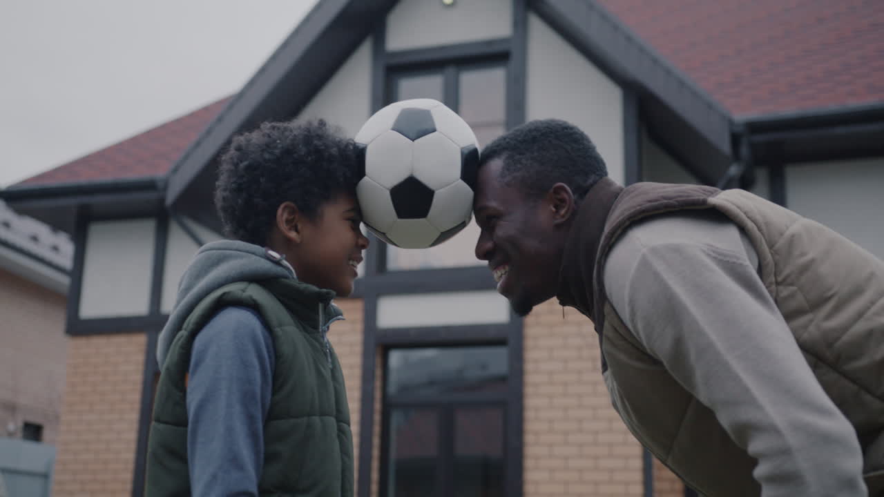 아버지 와 아들 이 축구 공 을 가지고 놀고 있다