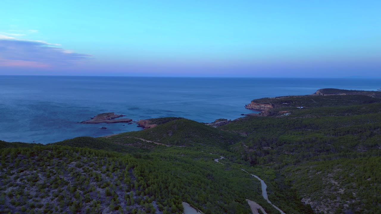 Rolling green hills meeting a calm Mediterranean Sea under a twilight sky. Spectacular aerial view flight panorama overview drone