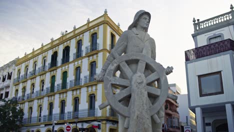 Gimbal-Se-Mueve-A-La-Izquierda-Con-Una-Estatua-De-Un-Marinero-En-El-Frente-En-El-Puerto-De-La-Ciudad-De-Ibiza,-España,-Durante-La-Puesta-De-Sol