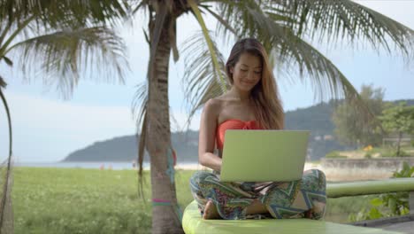 beautiful mixed race girl sitting crossed legged and browsing laptop