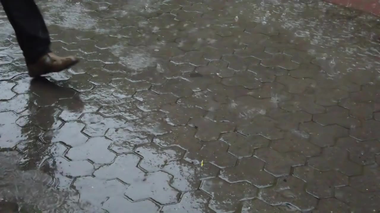 Hujan di kota. Tetesan hujan jatuh di trotoar.
