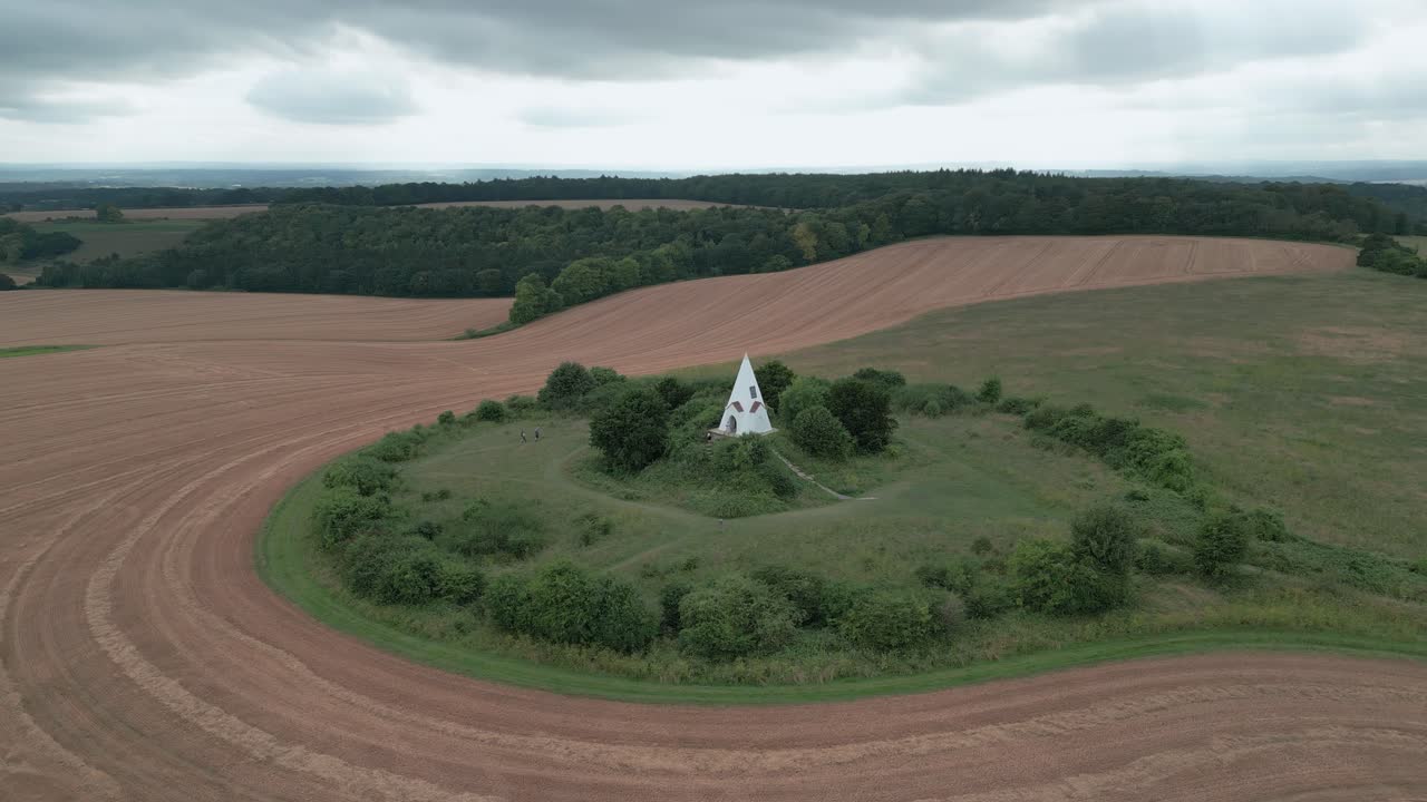 Aerial view orbiting Farley mount hilltop monument surrounded by countryside ploughed farmland