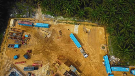 cinematic drone footage of onshore drilling rig equipment structure for oil exploration and exploitation in the middle of jungle surrounded by palm oil trees during sunset and high oil price