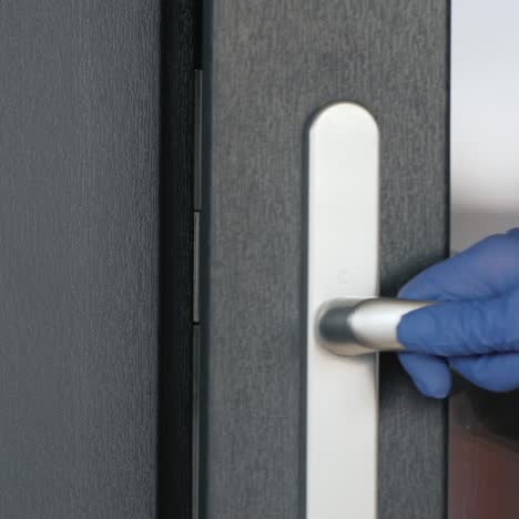 a man in protective latex gloves leaves the house - close-up of the doorknob