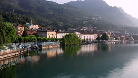 Drone-view-of-Lake-Iseo-at-sunrise,-on-the-left-the-city-of-Lovere-which-runs-along-the-lake,Bergamo-Italy